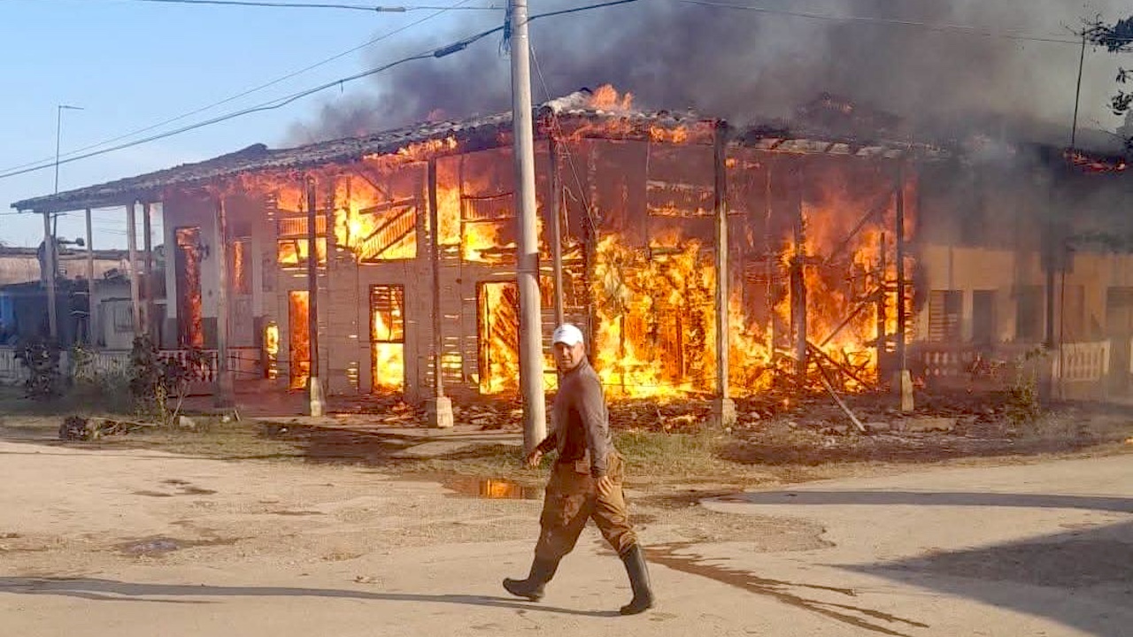 Un hombre pasa frente a casas ardiendo en Placetas, Villa Clara.