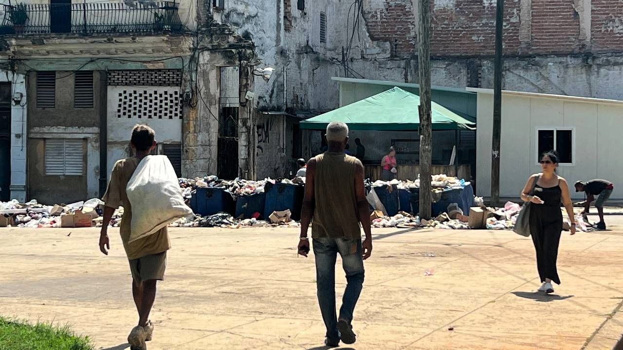Personas caminan cerca de un basurero en La Habana.
