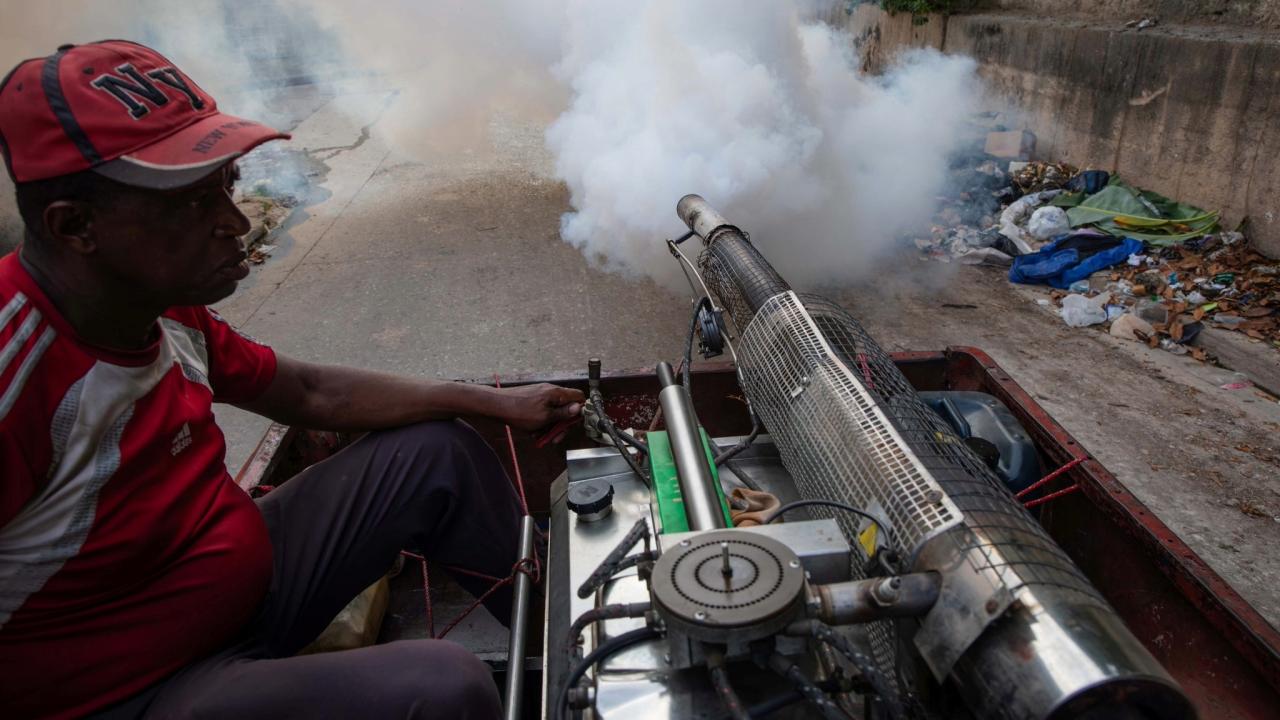 Un trabajador de la fumigación en Matanzas y un basurero al fondo.