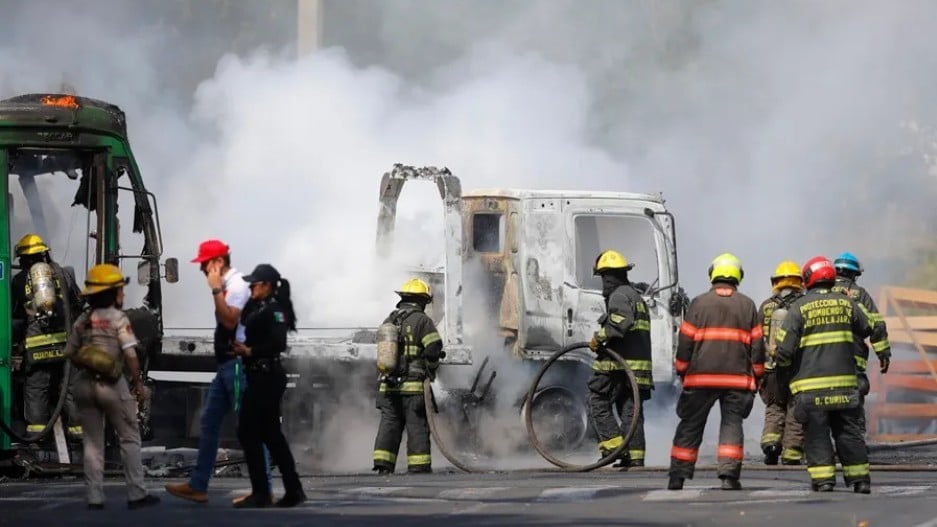Bomberos de Guadalajara intentan apagar un vehículo incendiado por el crimen organizado en aparente retaliación por operativos contra El Mencho, este 22 de febrero, en Guadalajara.