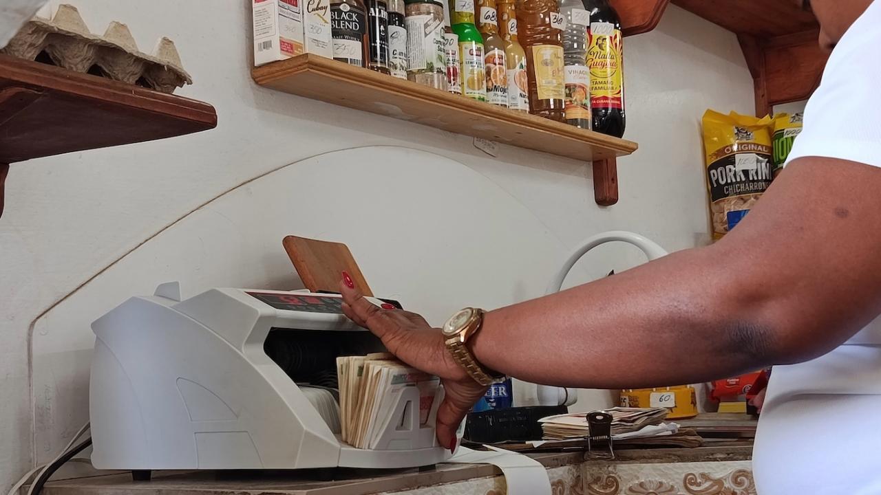 Una empleada cuenta billetes en una máquina.