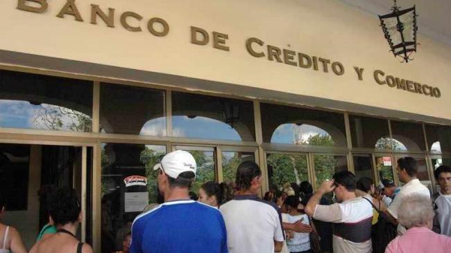 Cola ante un banco en Cuba.
