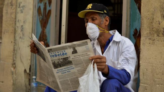 Un cubano lee un diario oficial.