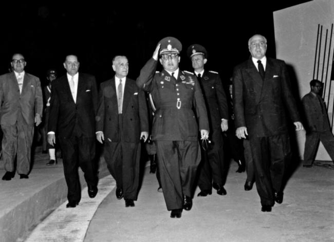 Alejo Carpentier (segundo por izq.), en el séquito de Pérez Jiménez, que saluda militarmente, Caracas, 1954. 
