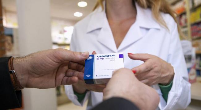 Una farmaceuta entrega una caja de Viagra. 