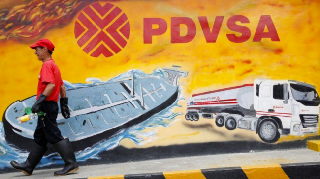 Un trabajador camina frente a un mural de PDVSA en Caracas, Venezuela.