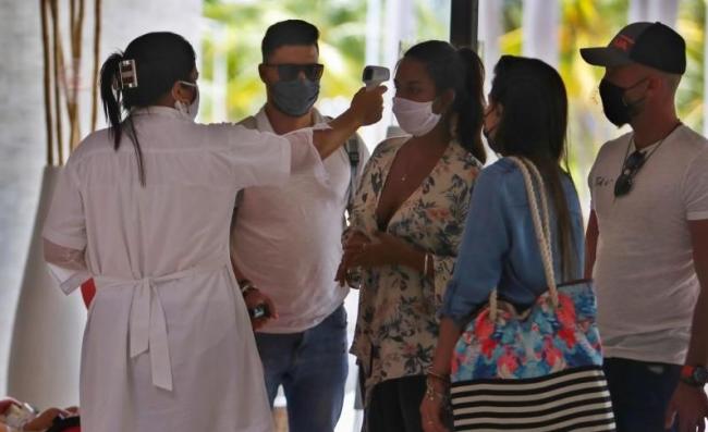 Una doctora toma la temperatura a vacacionistas cubanos.