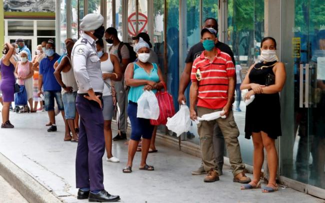 Un policía frente a una fila de personas en Cuba durante la pandemia del coronavirus.
