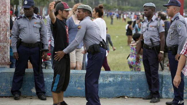 Policías cubanos registran a un hombre.
