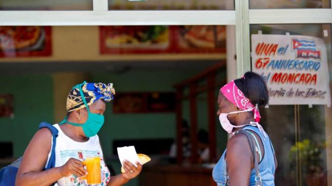 Dos mujeres cubanas conversan en la entrada de un establecimiento gastronómico.