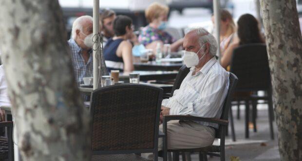 Personas con nasobuco en una terraza de España.