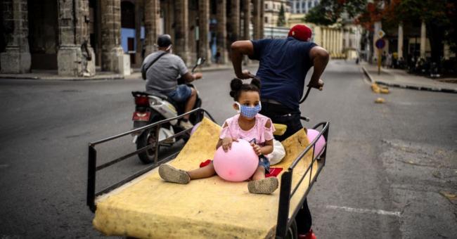 Una niña sobre una carretilla en La Habana.