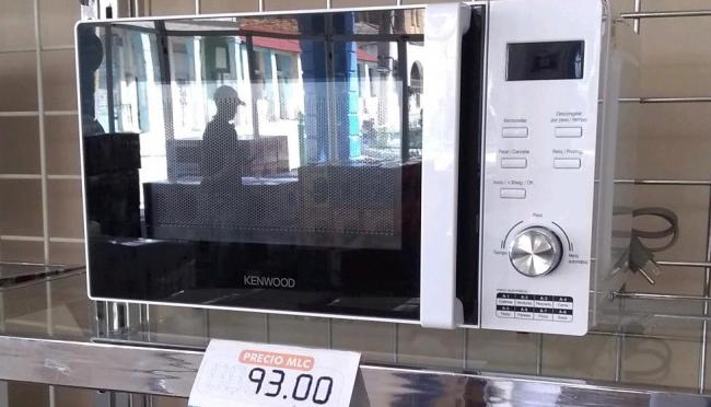 Un cliente reflejado en la puerta de un horno microondas en la tienda La Isla, de Mayarí, Holguín.