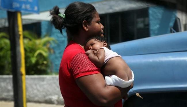 Una madre cubana carga a su recién nacido.