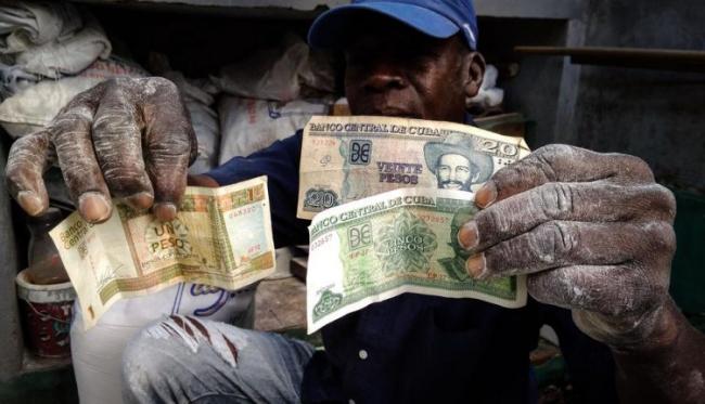 Un hombre sostiene pesos cubanos y pesos convertibles.