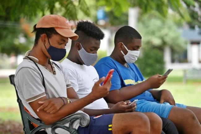 Cubanos conectados desde sus teléfonos en un parque.