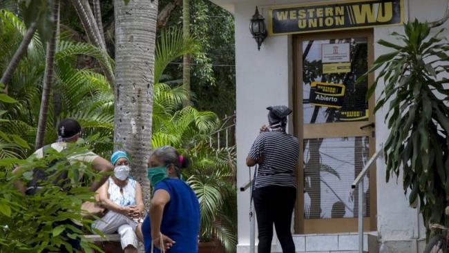 Un grupo de personas espera en la entrada de una oficina de Western Union en Cuba.