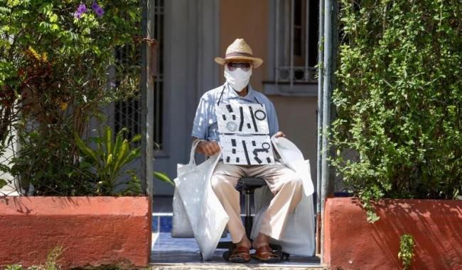 Un vendedor con mascarilla en las puertas de su casa.