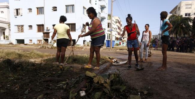 Cubanas barriendo una calle.