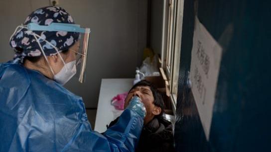 Una sanitaria realiza una prueba a un ciudadano en Wuhan