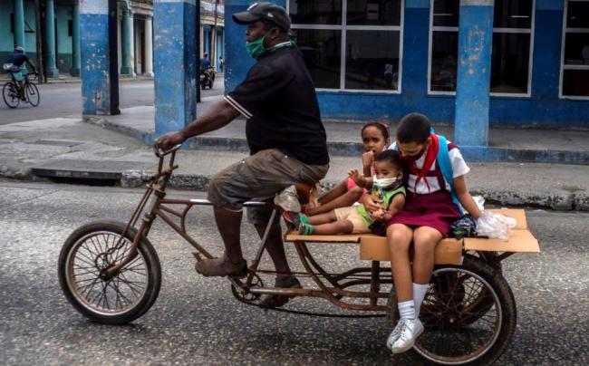 Una familia cubana se mueve en triciclo.