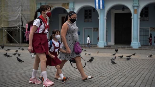 Una mujer cubana acompaña a dos niños a la escuela.