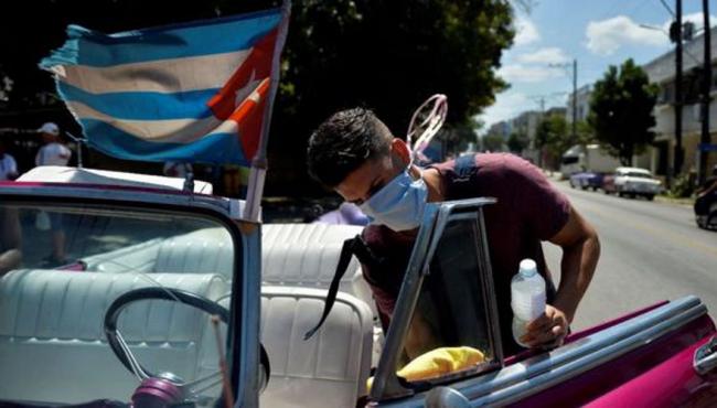 Un taxista privado limpia su vehículo en La Habana.