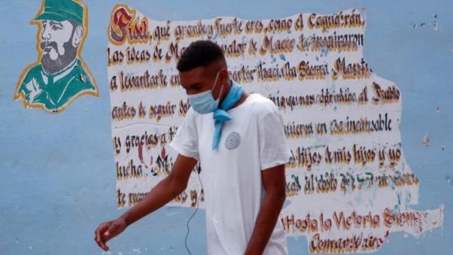 Un hombre pasa delante de una pared pintada con una frase de Fidel Castro.