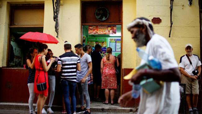 Cubanos hacen fila frente a una cafetería privada.