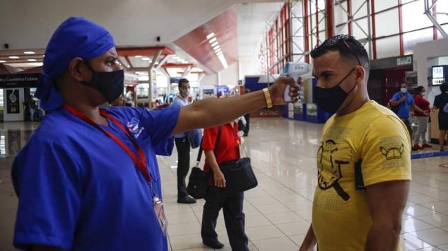 Un doctor toma la temperatura a un viajero en el aeropuerto de La Habana.