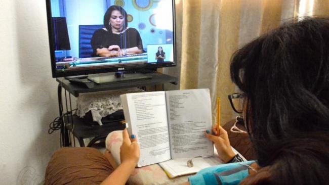 Una estudiante cubana observa las clases por televisión.