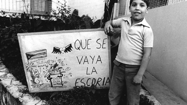 Un niño habanero en 1980 junto a un cartel contra los cubanos que se marchaban del país.