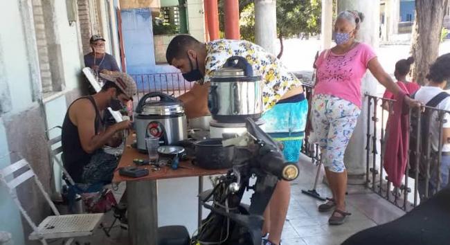 Un 'cuentapropista' reparador de ollas de presión y sus clientes en La Habana.