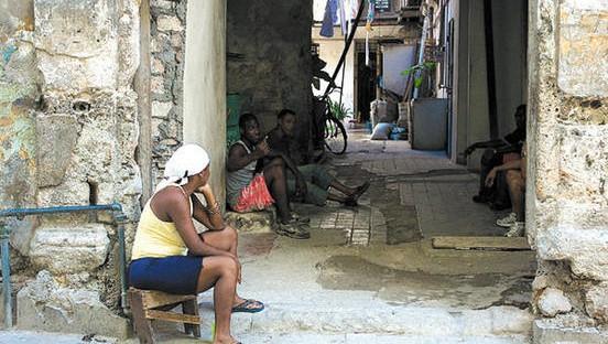 Personas en la entrada de una cuartería en Cuba.