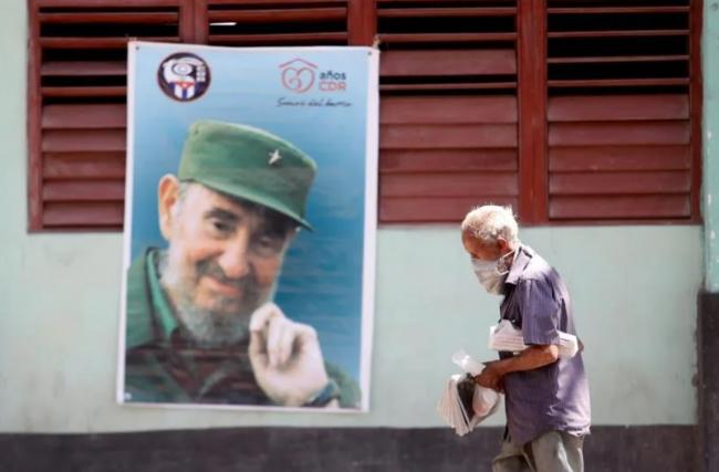 Un anciano pasa por delante de un póster de Fidel Castro y los CDR.