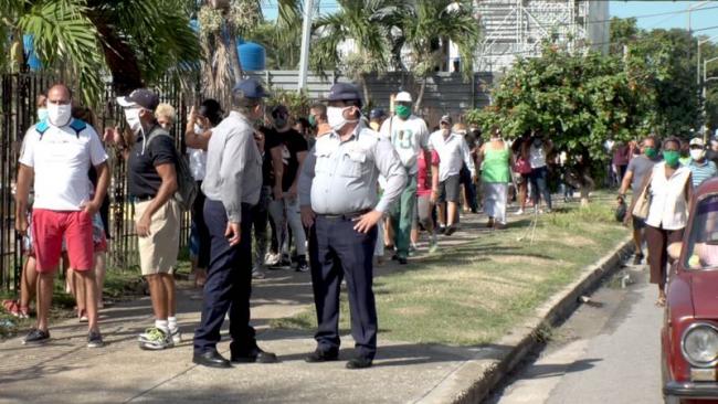 Dos policías cubanos vigilan una cola en una tienda en MLC en La Habana. 