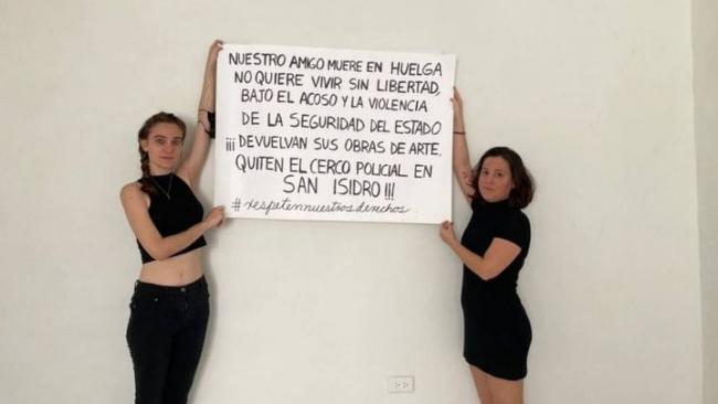 La artista Camila Lobón y la poeta Katherine Bisquet sostienen un cartel antes de salir a manifestarse.