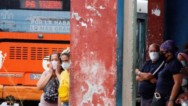 Personas aguardan en una parada de ómnibus en Cuba.