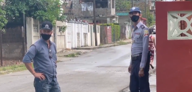 Un agente de la Seguridad del Estado y un policía vigilan la casa de Iliana Hernández en La Habana.