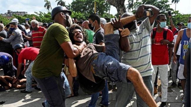 Un manifestante en Cuba reducido por oficiales vestidos de civil de la policía política.