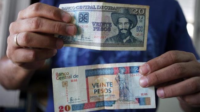 Un cubano enseña un billete de 20 pesos y otro de los desaparecidos CUC.