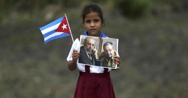 Una niña alumna de primaria sostiene una foto de los Castro.