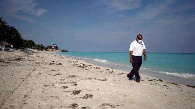 Un trabajador del turismo camina por la playa de Varadero vacía.