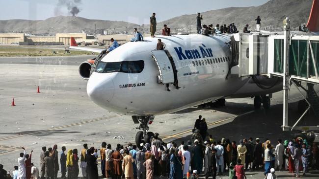 Afganos desesperados intentan huir en aviones de EEUU tras la toma de Kabul por los talibanes.