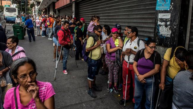 Venezolanos en una cola para comprar víveres.