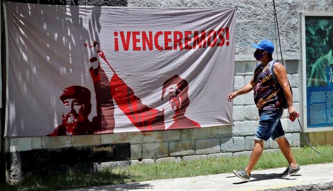 Un cubano camina frente a un cartel de propaganda política.