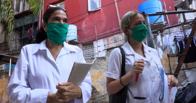 Una doctora y una estudiante cubanas haciendo pesquisas durante la pandemia con mascarillas quirúrgicas de tela.