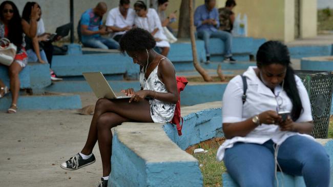 Cubanos conectados a internet en una plaza pública.