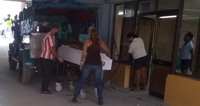 Familiares subiendo un féretro a un transpote privado en Santiago de Cuba.