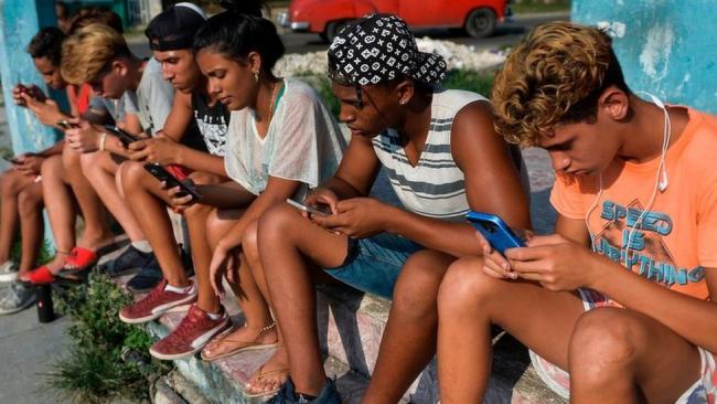 Jóvenes cubanos conectados a Internet con sus teléfonos móviles.